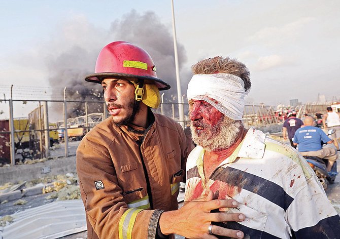 A wounded man is helped by a firefighter near the scene of an explosion in Beirut on August 4, 2020. (AFP / ANWAR AMRO)