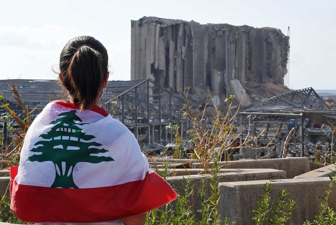 A Lebanese youth wrapped in the national flag looks at the damaged grain silos at Beirut's port, on August 11, 2020. (AFP)
