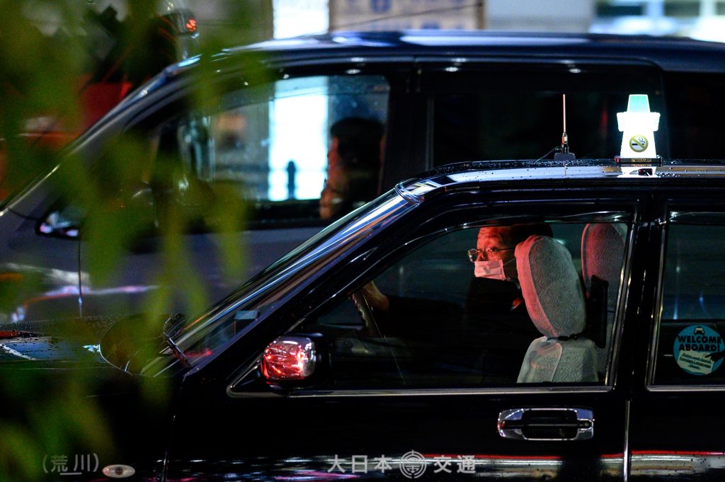 A taxi driver wearing a face mask, amid concerns about the spread of COVID-19 novel coronavirus, sits in his car in the Akihabara district of Tokyo on March 8, 2020. (AFP)