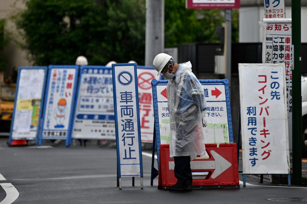 A restaurant employee waits for customers on a quiet street near Tokyo railway station. (AFP)