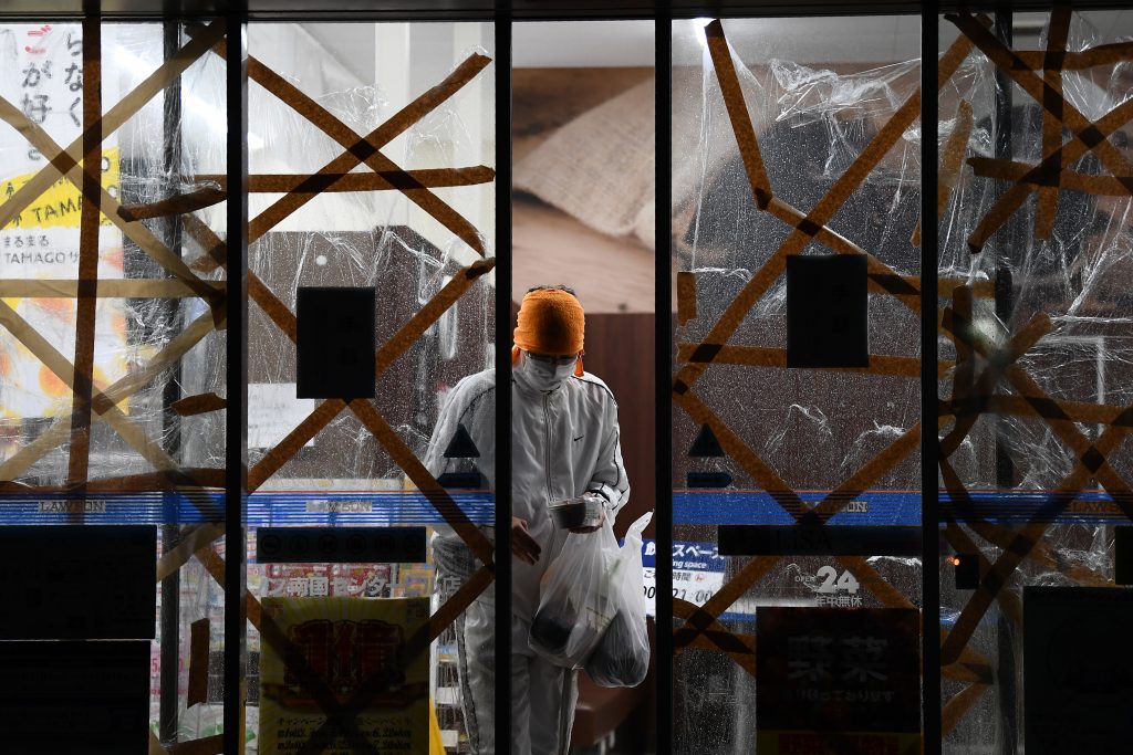 A person leaves a barricaded convenience store on September 6, 2020 as Typhoon Haishen approaches. (AFP)
