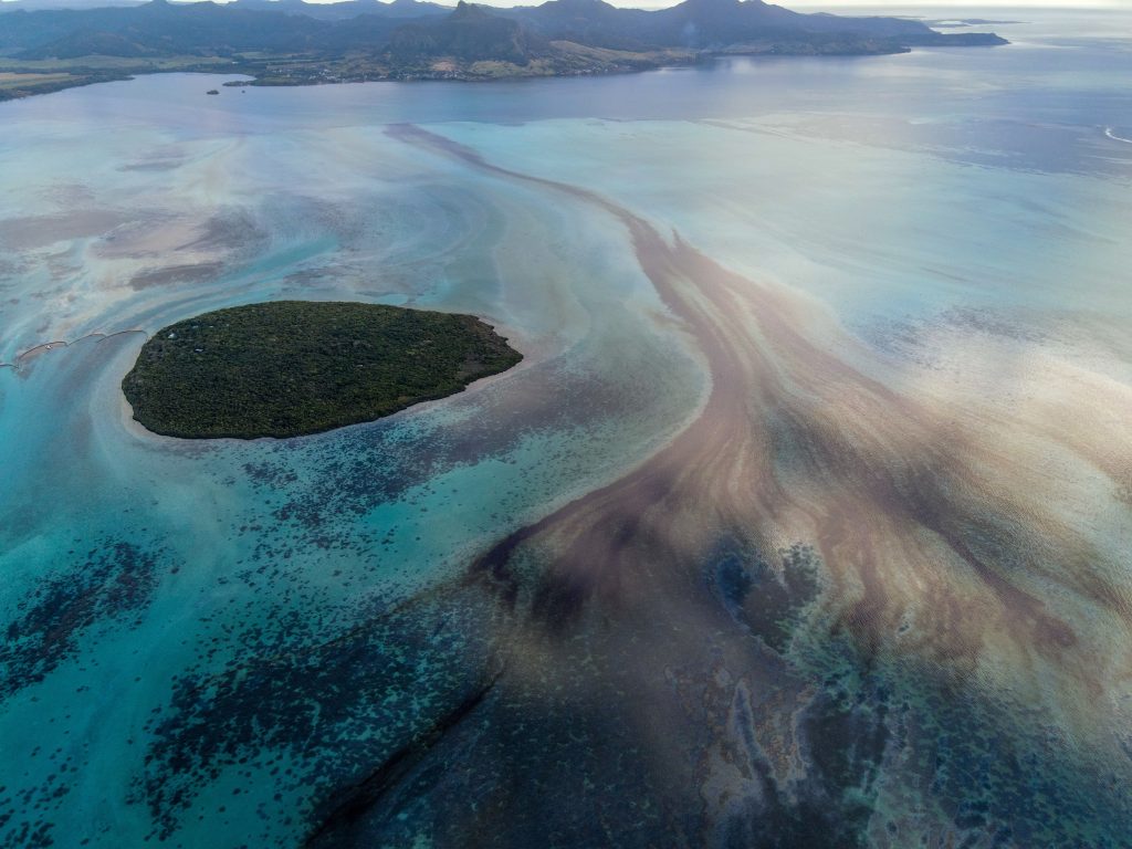 In this file photo taken on August 08, 2020 This aerial view taken shows the Pointe d'Esny, and the Grand Port in the background, with a large patch of leaked oil and the vessel MV Wakashio, belonging to a Japanese company but Panamanian-flagged, that ran aground near Blue Bay Marine Park off the coast of south-east Mauritius. (AFP)