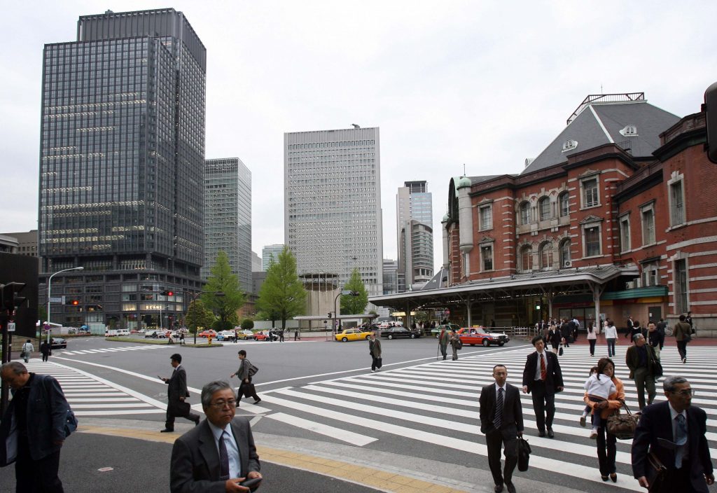 Pedestrians walk past the Shin-Marunouchi Building in front of Tokyo Station, 24 April 2007. (AFP)
