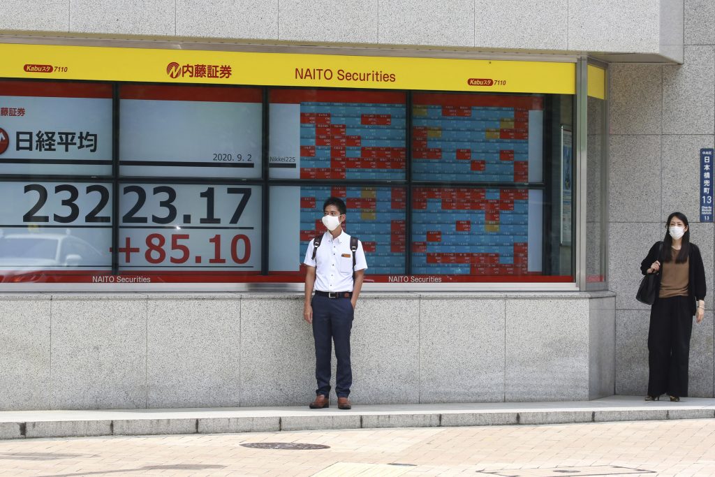 People stand by an electronic stock board of a securities firm in Tokyo, Wednesday, Sept. 2, 2020. Asian shares were mixed on Wednesday after another U.S. rally spurred by positive economic data, even while the coronavirus pandemic has regions around the world battling recessions. (AP Photo)