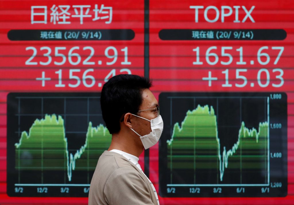 A passerby wearing a protective mask stands in front of an electronic board showing Japan's Nikkei and Topix average outside a brokerage, amid the coronavirus disease (COVID-19) outbreak, in Tokyo, Japan, sep. 14, 2020. (File photo/ Reuters)