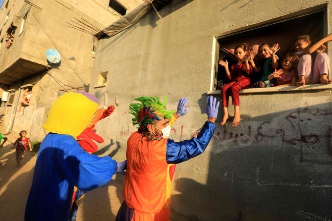 A clown and a person wearing a duck costume entertain Palestinian children during a lockdown imposed by the local authorities following a surge in coronavirus cases, in Khan Younis in the southern Gaza Strip, on September 2, 2020. (AFP)