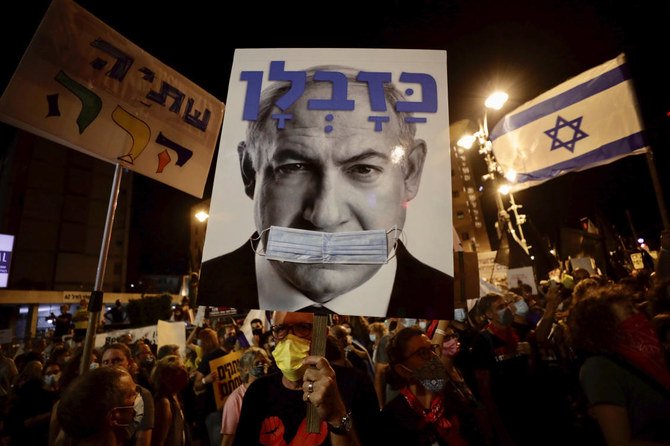 Israeli protesters hold signs during a demonstration against Israeli Prime Minister Benjamin Netanyahu outside the Prime Minister's residence in Jerusalem, Saturday, Sept. 12, 2020. (AP/Sebastian Scheiner)