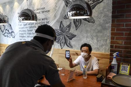 A customer (right) places his food order by using his cellphone. (AFP)