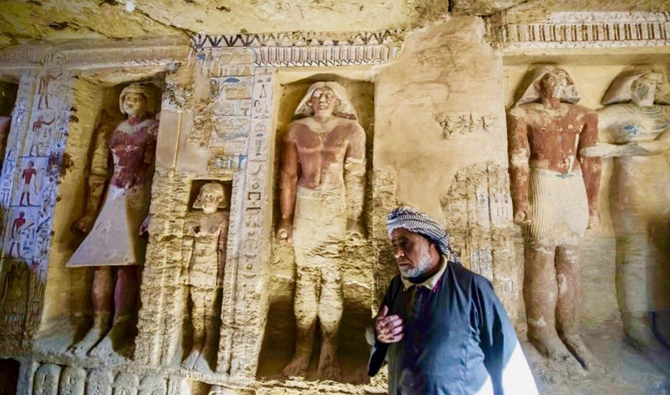 An Egyptian archaelogical laborer is seen walking near deities in a newly discovered tomb at Saqqara necropolis, on Saturday. (AFP)