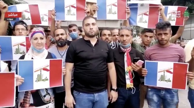 Political activists in Beirut, holding images of mixed flags of Hezbollah and France, show their opposition to what they see as France’s arrangement with Iran to pick Mustapha Adib as the new premier, who, they allege, is no different from his predecessor Hassan Diab. (Twitter)