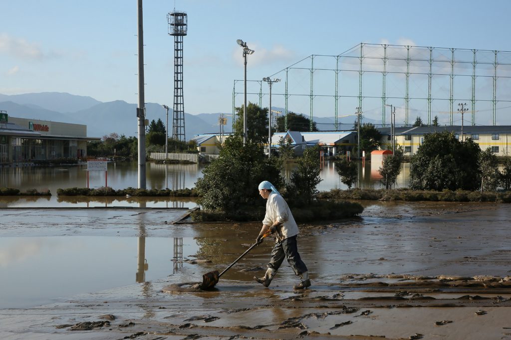 A resident removes mud from an area which was flooded by Typhoon Hagibis in Nagano on October 16, 2019. Rescuers in Japan worked around the clock on October 15 in an increasingly desperate search for survivors of a powerful weekend typhoon that killed more than 70 people and caused widespread destruction. (AFP)