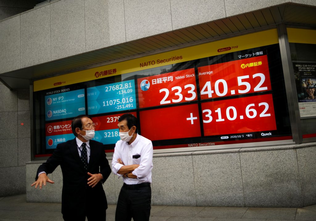 Men wearing protective face masks chat in front of a screen displaying Nikkei share average and world stock indexes outside a brokerage, amid the coronavirus disease (COVID-19) outbreak, in Tokyo, Japan Oct.5, 2020. (File photo/ Reuters)