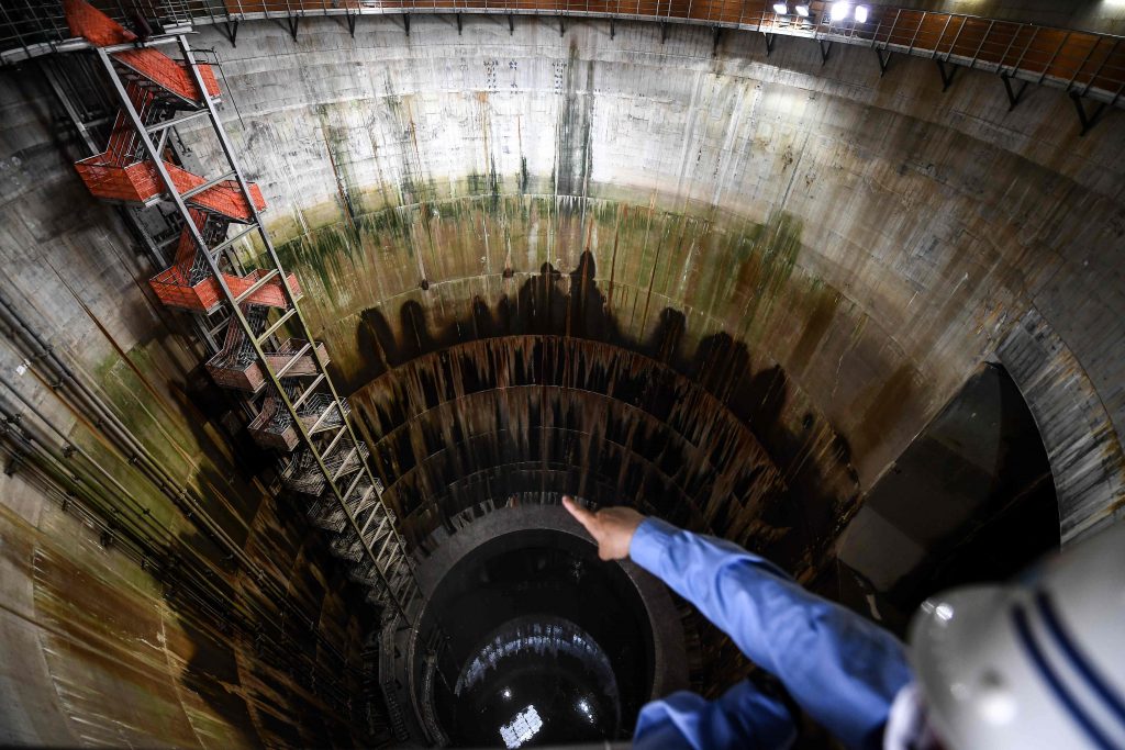 In this photo taken on September 3, 2020, an employee points down the 72.1 meter-deep number 1 tank of the metropolitan outer underground discharge channel in Kasukabe, Saitama prefecture. It has been called Japan's underground 
