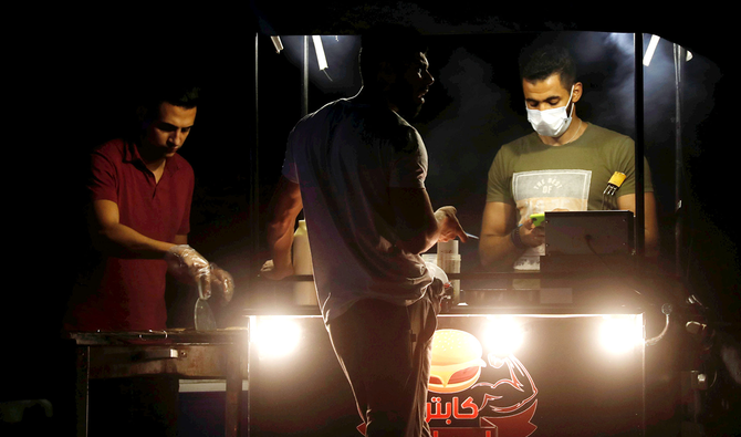 A street vendor wearing a protective face mask grills burgers on a street in the Cairo suburb of Maadi. (Reuters)