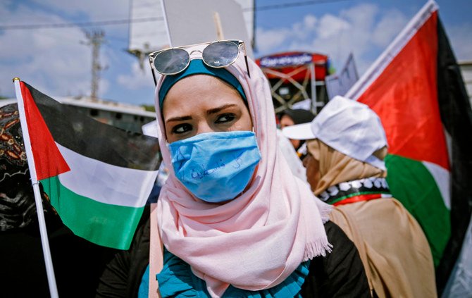 A Palestinian protester waves the national flag during a demonstration in the village of Kfar Qaddum in the Israeli-occupied West Bank against the Jewish state's plans to annex part of the territory, on June 6, 2020. (Photo by JAAFAR ASHTIYEH / AFP)