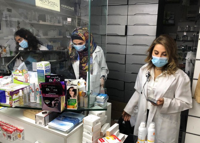 Pharmacist Siham Itani wearing a protective mask looks at her mobile phone inside her pharmacy in Beirut, Lebanon. (File/Reuters)