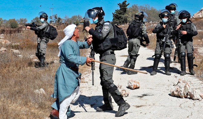 A Palestinian man confronts an Israeli forces after they intervened in scuffles between Jewish settlers and Palestinian farmers trying to access their lands to harvest olives, in the West Bank village of Burqah, on October 16, 2020. (AFP)