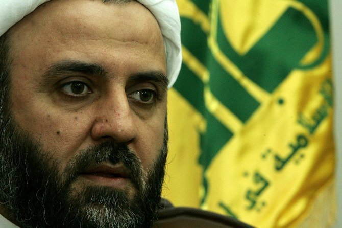 Sheikh Nabil Qaouk, Hezbollah’s military chief in south Lebanon, sits in front of the militia’s flag in Tyre in 2006. (File/AFP)