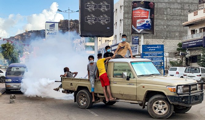 Youths wearing masks as a precaution due to COVID-19 coronavirus disease, sit in the back of a truck carrying out a fumigation in an area in Yemen's southern coastal city of Aden on May 5, 2020, as part of a campaign to prevent the spread of insect-borne diseases such as malaria, dengue fever, and Chikungunya virus amidst the novel coronavirus pandemic. (AFP)
