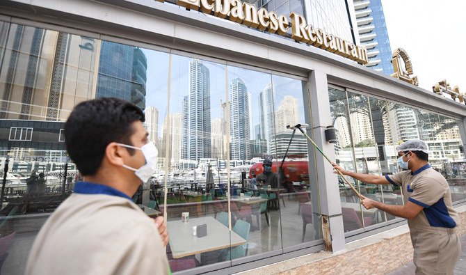 Labourers, wearing protective face masks, disinfect the front of restaurant in Dubai's marina on March 16, 2020. (AFP)