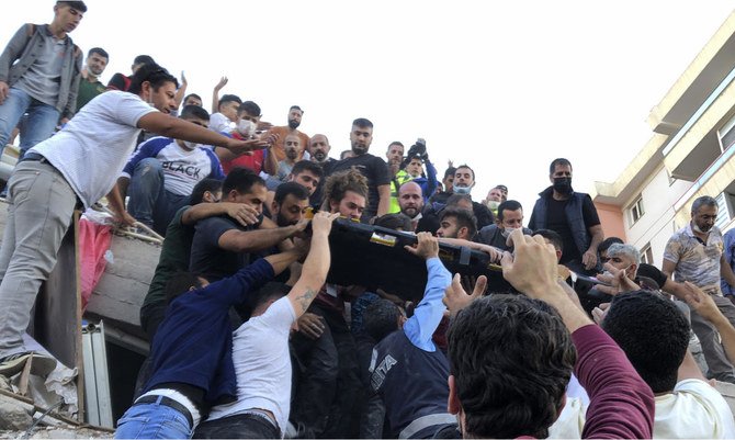 Rescue workers carry a wounded person saved from the debris of a collapsed building, in Izmir, Turkey, Friday, Oct. 30, 2020. (AP/Ismail Gokmen)