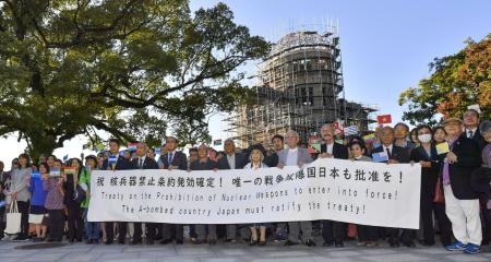 Members of Atomic Bomb survivors groups gather, holding a banner calling for Japanese government to ratify the Treaty on the Prohibition of Nuclear Weapons, with the Atomic Bomb Dome in background, in Hiroshima, western Japan, Sunday, Oct. 25, 2020. The United Nations confirmed Saturday that 50 countries have ratified the Treaty on the Prohibition of Nuclear Weapons, known as the TPNW, paving the way for its entry into force in 90 days. (Kyodo News via AP)