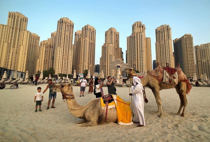 Tourists take photos with camels on the beach at Jumeirah Beach Residence in Dubai, UAE. (File/AP)