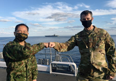 Lieutenant General Kevin Schneider, commander of US Forces Japan, and General Koji Yamazaki, Japan's top military commander of Chief of Staff of Joint Staff greet each other on the Japan Maritime Self-Defense Force helicopter carrier JS Kaga, with the USS Ronald Reagan aircraft carrier in the background, during Keen Sword, amid the coronavirus disease (COVID-19) outbreak, at mid-sea off south of Japan, October 26, 2020. (Reuters)