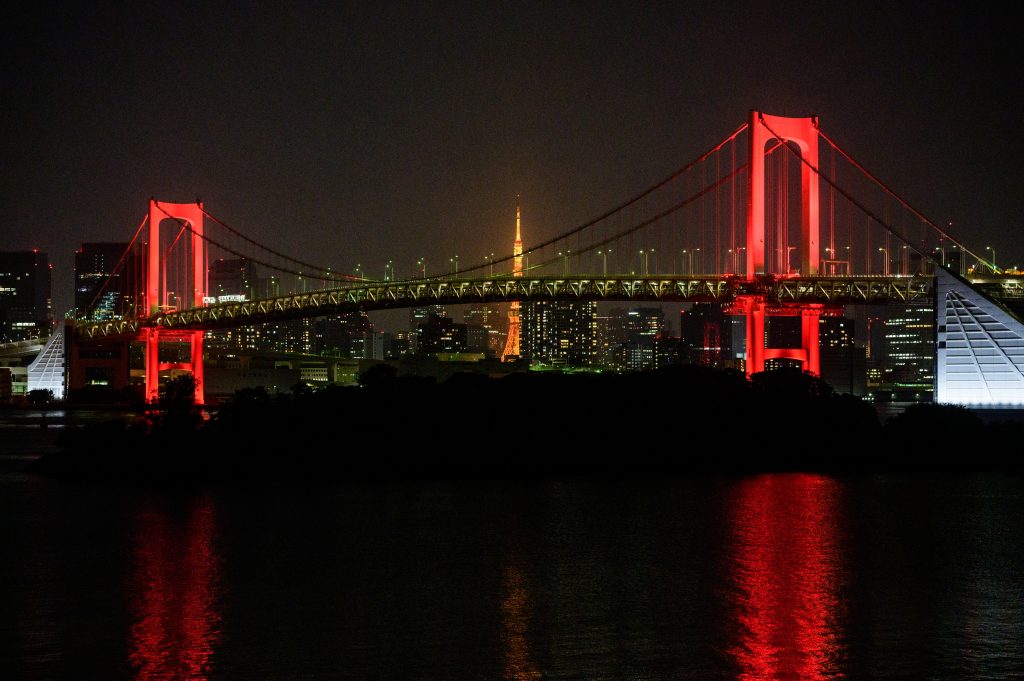 The Rainbow Bridge is seen lit up at night in red, after Tokyo government decided to issue an alert due to an increase in COVID-19 coronavirus cases in Tokyo, June. 2, 2020. (AFP)