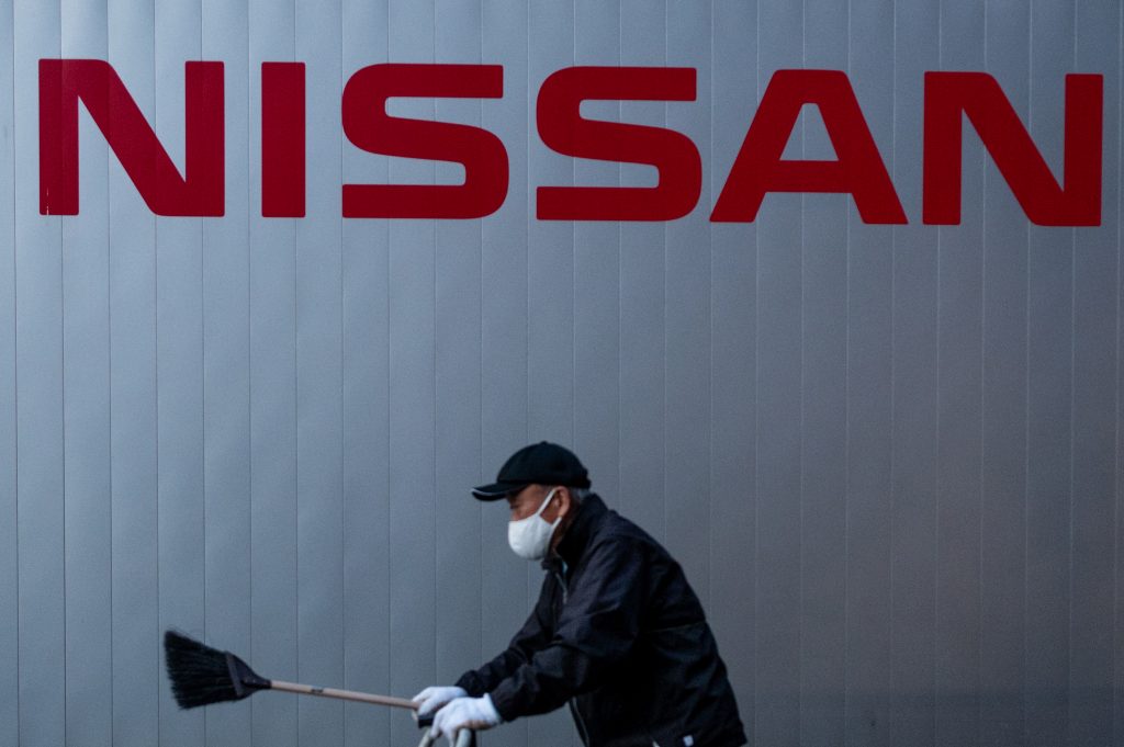 This photo taken on November 11, 2020 shows a worker walking in front of signage at a Nissan dealership in Tokyo. (AFP)