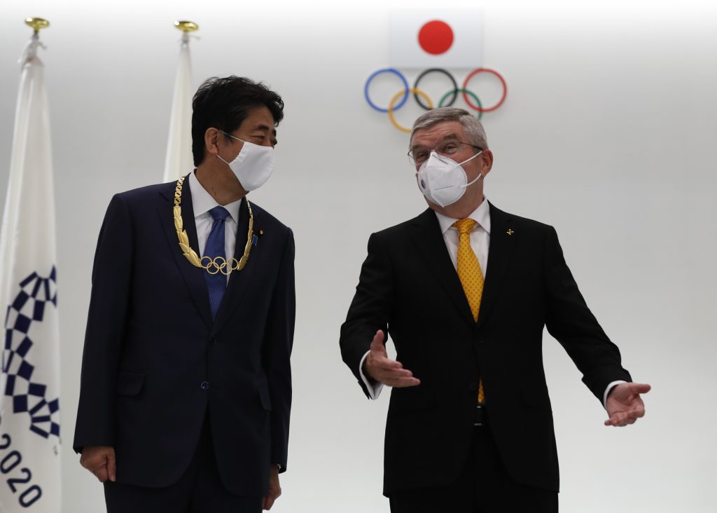 International Olympic Committee (IOC) president Thomas Bach (R) and Japan's former prime minister Shinzo Abe bump fists after Abe was awarded the Olympic Order during a ceremony at the Japan Olympic Museum in Tokyo on November 16, 2020. (AFP)