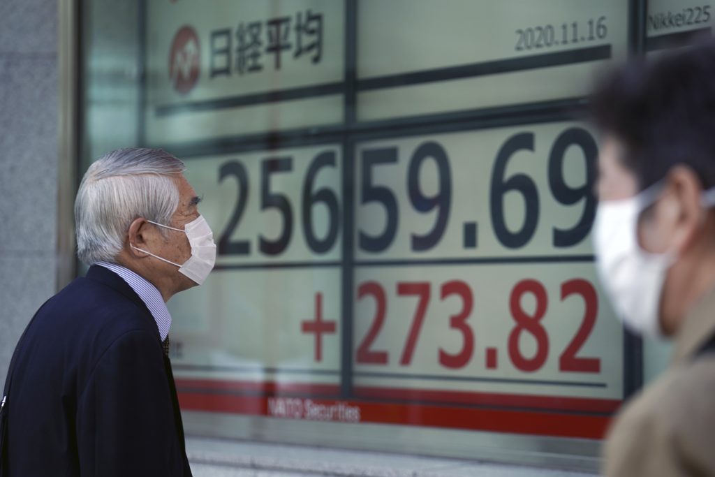 A man wearing a mask against the spread of the coronavirus looks at an electronic stock board showing Japan's Nikkei 225 index at a securities firm in Tokyo Monday, Nov. 16, 2020. Shares started out the week on a strong footing after the Standard & Poors 500 hit a fresh high on Friday, with strong data from Japan and China fueling optimism over economic recoveries even as coronavirus caseloads surpass earlier records.(AP Photo/Eugene Hoshiko)