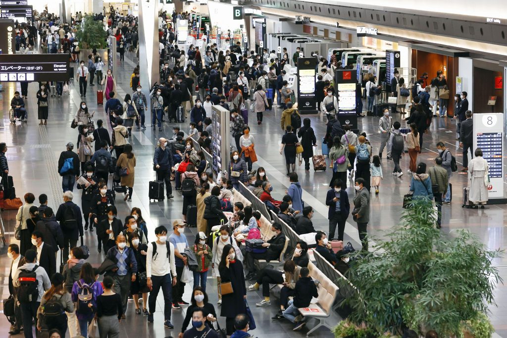People make their way at a departure lobby of Haneda airport in Tokyo Saturday, Nov. 21, 2020. Japan is scaling back on the government-backed â€œGoToâ€' campaign to encourage travel and dining out, as the number of confirmed COVID-19 cases reached a record for the third day straight, Saturday. (Kenzaburo Fukuhara/Kyodo News via AP)