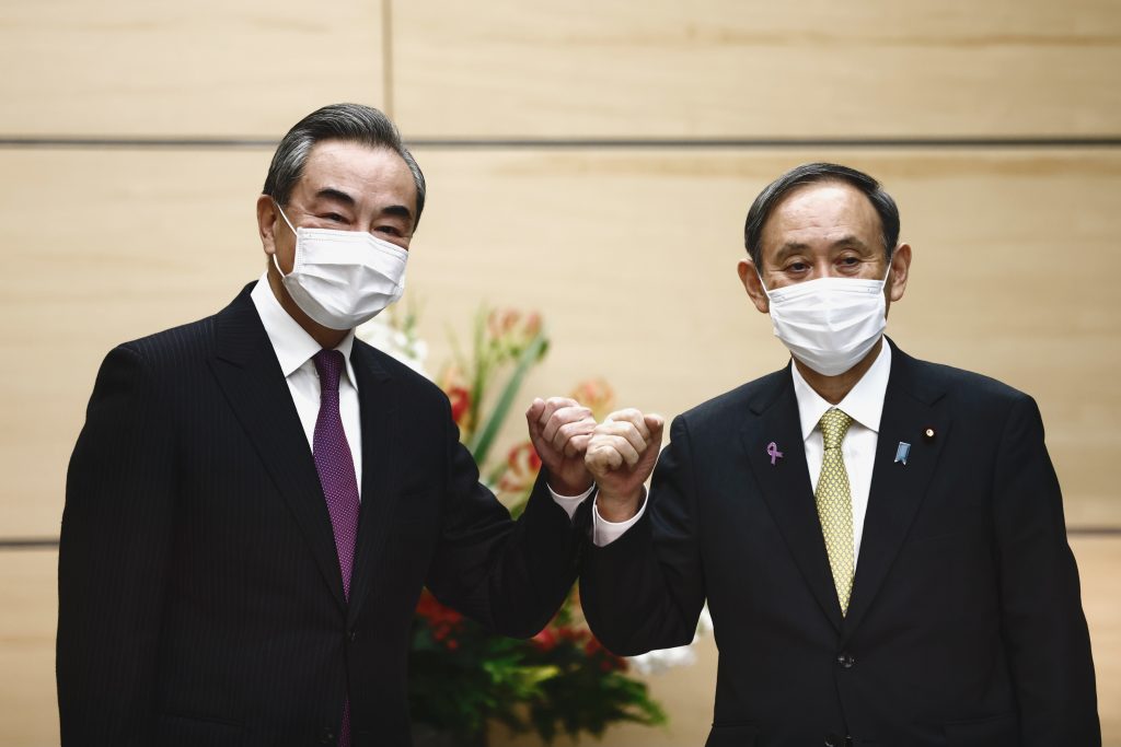Japan's Prime Minister Yoshihide Suga, right, bumps elbows with China's Foreign Minister Wang Yi at the start of their meeting in Tokyo, Nov. 25, 2020. (File photo/AP)