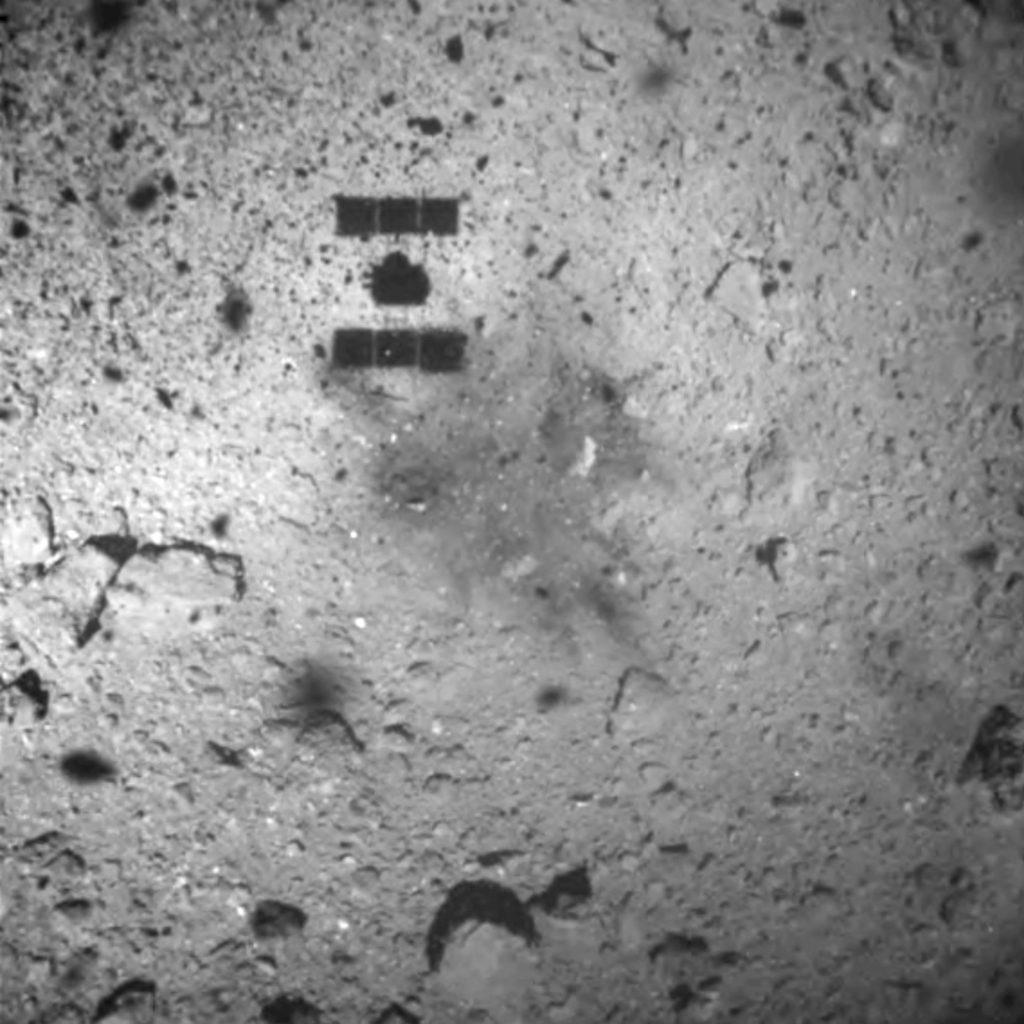 This Feb. 22, 2019, file image released by the Japan Aerospace Exploration Agency (JAXA) shows the shadow, center above, of the Hayabusa2 spacecraft after its successful touchdown on the asteroid Ryugu. The Japanese spacecraft is nearing Earth after a yearlong journey home from a distant asteroid carrying soil samples and data that could provide clues to the origins of the solar system, a space agency official said Friday, Nov. 27, 2020. (JAXA via AP, File)