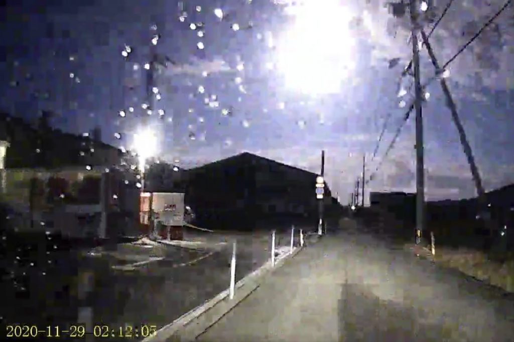 This image made from a drive recorder shows a brightly burning meteor, center top, over a road in Tokushima prefecture, southwestern Japan, Sunday, Nov. 29, 2020. The brightly burning meteor was seen plunging from the sky in wide areas of Japan, capturing attention on television and social media. The meteor glowed strongly as it rapidly descended through the Earth's atmosphere on Sunday. Many people in western Japan reported on social media seeing the rare sight. (Kamio via AP)