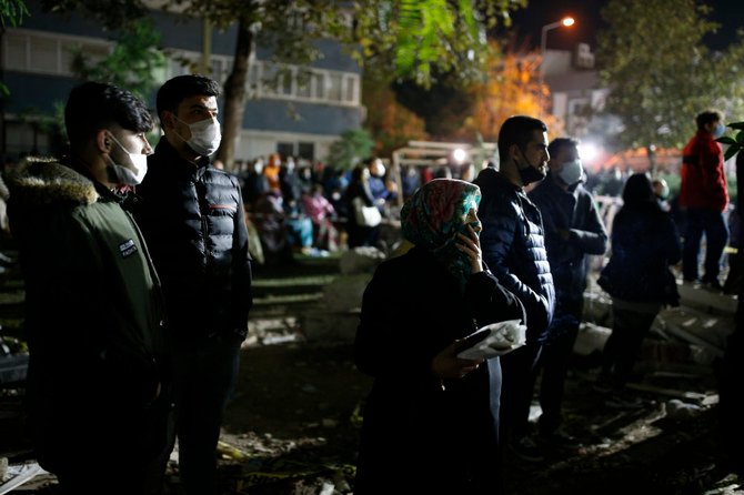 Local residents, staying outdoors for fear of aftershocks, watch as members of rescue services search in the debris of a collapsed building for survivors in Izmir, Turkey, on Oct. 31, 2020. (AP Photo/Emrah Gurel)