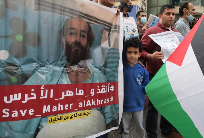 Palestinians carry placards demanding the release of administrative detainee in Israeli custody Maher al-Akhras during a demonstration Hebron on November 3, 2020, after his health has deteriorated while on hunger strike for nearly 100 days. (AFP)