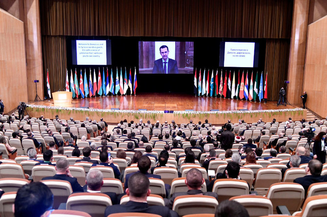 Syria's President Bashar Assad is seen on screen as he speaks during the international conference on the return of Syrian refugees in Damascus on Nov. 11, 2020. (SANA/Handout via REUTERS)