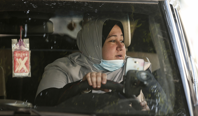 The first female Palestinian taxi driver in the Gaza Strip, Nayla Abu Jubbah, 39, sits at her vehicle as she works in Gaza City on November 17, 2020. (AFP)
