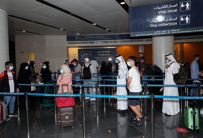 Passengers, wearing protective face mask due to the Covid-19 pandemic, stand in a queue at the Muscat international airport in the Omani capital on October 1, 2020. (File/AFP)