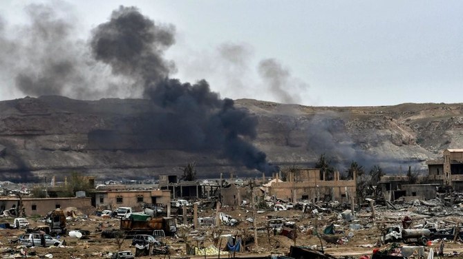 Smoke rises behind destroyed vehicles and damaged buildings in the village of Baghouz of Syria’s eastern Deir Ezzor province near the Iraqi border in this March 24, 2019 file photo. (AFP)