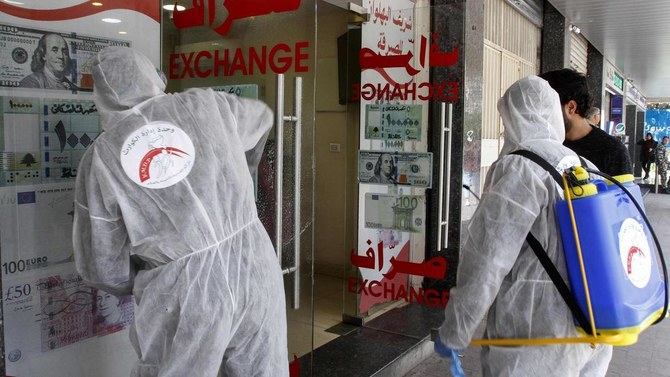 Volunteers with Lebanon's Disaster Management Unit disinfect a currency exchange in the southern city of Saida on March 12, 2020 to prevent the spread of coronavirus. (AFP)