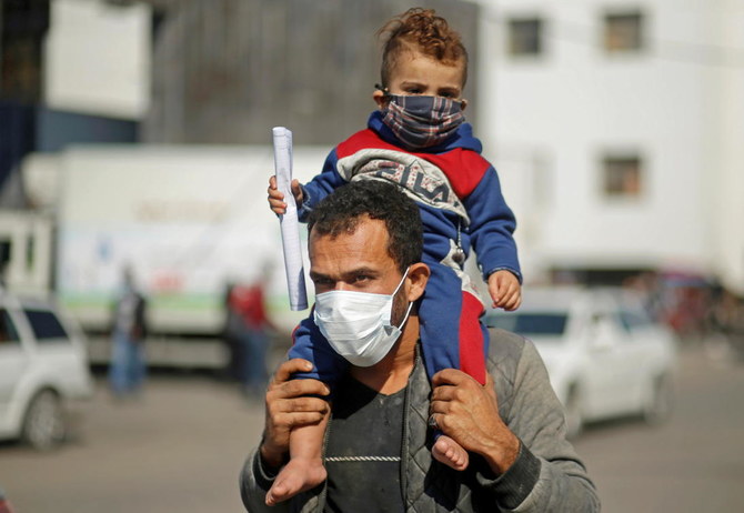 A Palestinian man carries his son on his shoulders as he leaves Shifa hospital amid the coronavirus disease (COVID-19) outbreak, in Gaza City November 22, 2020. (Reuters)