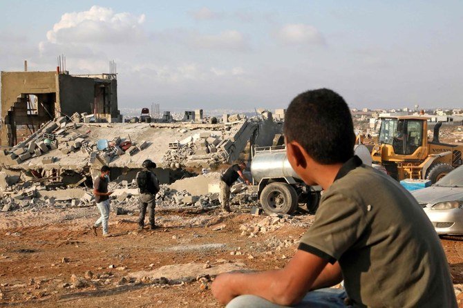 A Palestinian boy watches as Israeli machinery demolish a house located within the area C (where Israel retains control, including over planning and construction) near the Palestinian village of Yatta in the southern area of the West Bank town of Hebron, on November 2, 2020. (AFP)