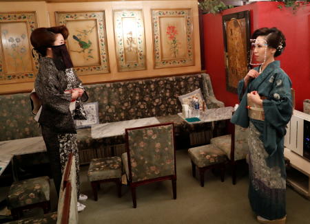 Bar hostesses Kasumi Mizusawa wearing a 'face veil mask' and Yuri Ichinose wearing a face shield, following the coronavirus disease (COVID-19) outbreak, prepare to open the bar at the club 'Ashida' in Tokyo, Japan, November 16, 2020. (Reuters)