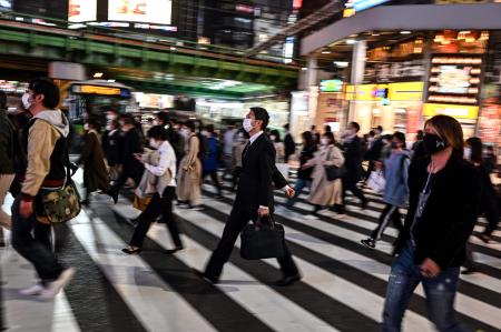 People cross a street at night in the Shinjuku area in Tokyo on November 18, 2020. (AFP)