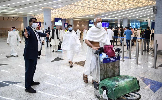 Pakistani travellers arriving in Saudi Arabia to perform Umrah walk with their luggage at King Abdulaziz International Airport in Jeddah on November 1, 2020. (AFP)