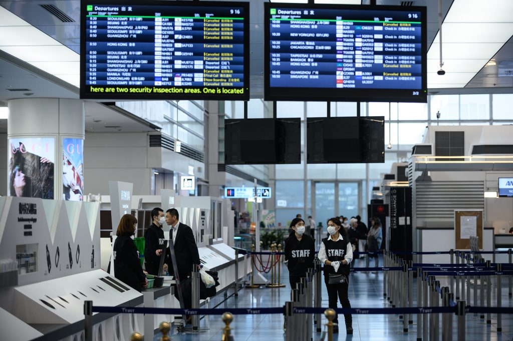 Staff members wearing face masks are seen at the departure hall of Tokyo's Haneda Airport, March. 10, 2020. (AFP)