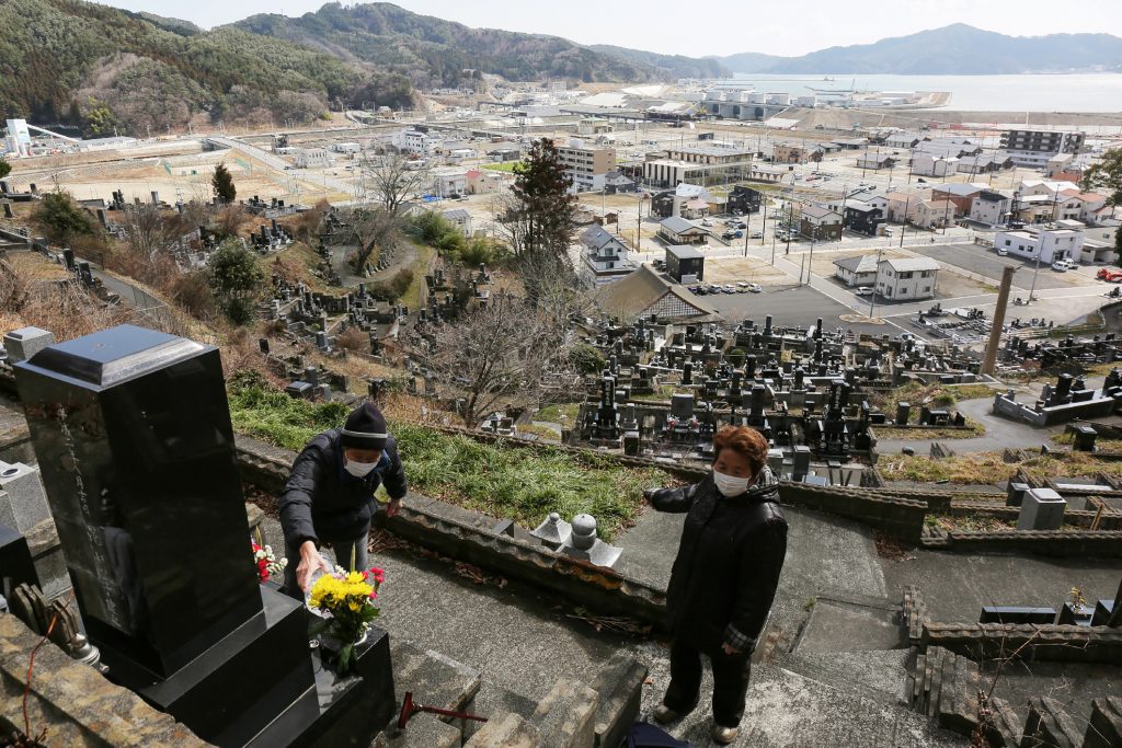 People lay flowers on their relatives' graves at a cemetery in Otsuchi, Iwate prefecture on March 11, 2020 on the ninth anniversary of the 2011 tsunami disaster. (AFP)
